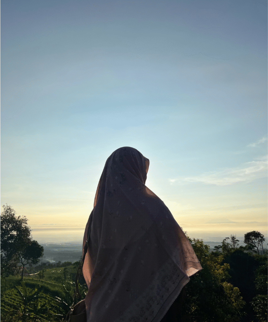 femme de dos avec un foulard noir qui contemple la nature et la mer